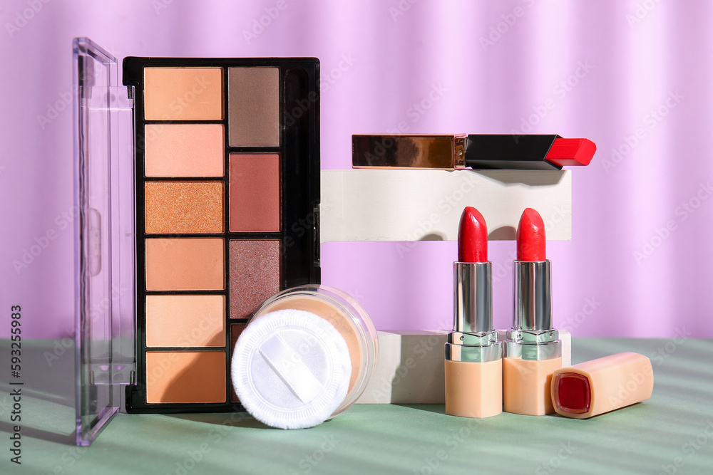 Decorative cosmetics with podium on table near lilac wall