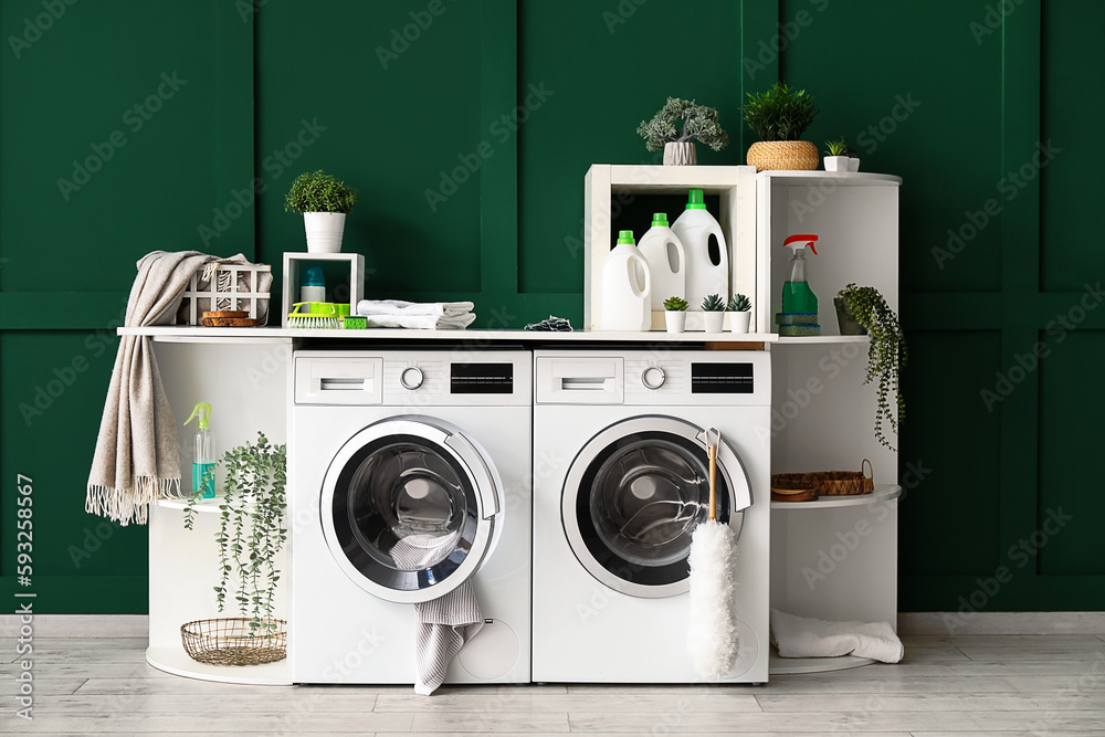 Interior of laundry room with washing machines, shelving units and artificial plants