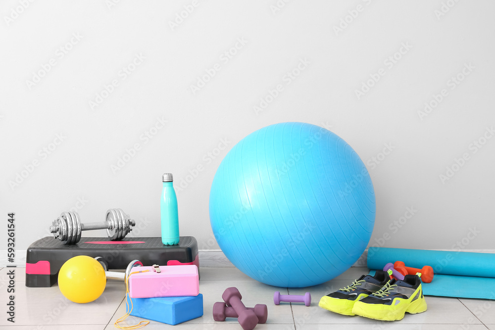 Sports equipment with sneakers near light wall in gym