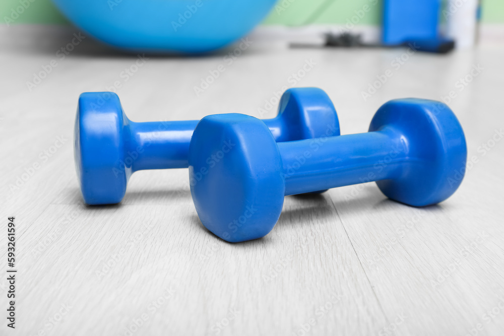 Blue dumbbells on floor in gym, closeup