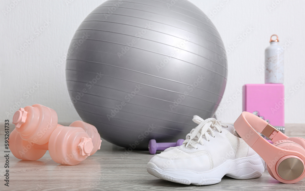 Sports equipment with sneakers and headphones near white wall in gym