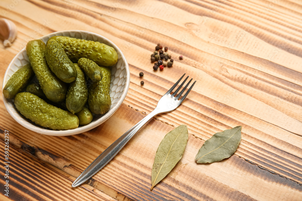 Bowl with tasty fermented cucumbers and ingredients on wooden background