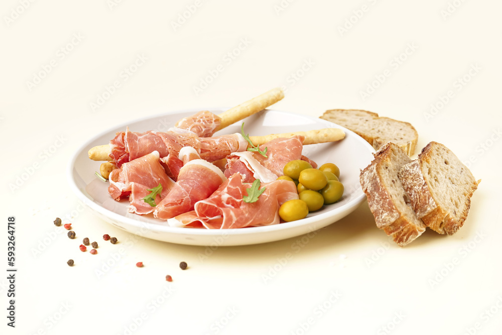 Plate of tasty jamon and Italian Grissini on yellow background