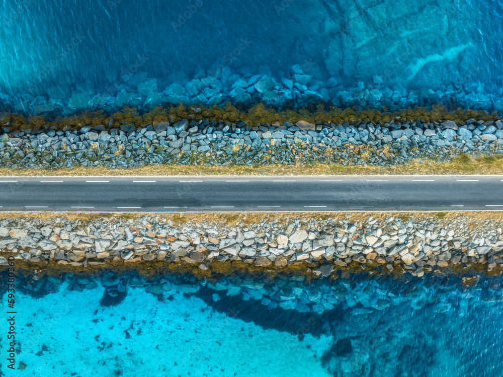 Aerial view of road, sea, stones at sunset in Lofoten Islands, Norway. Landscape with beautiful brid