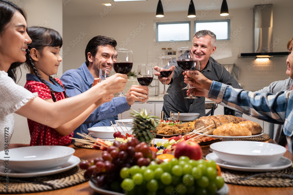 Multi-ethnic big family having dinner, enjoy evening party in house. 