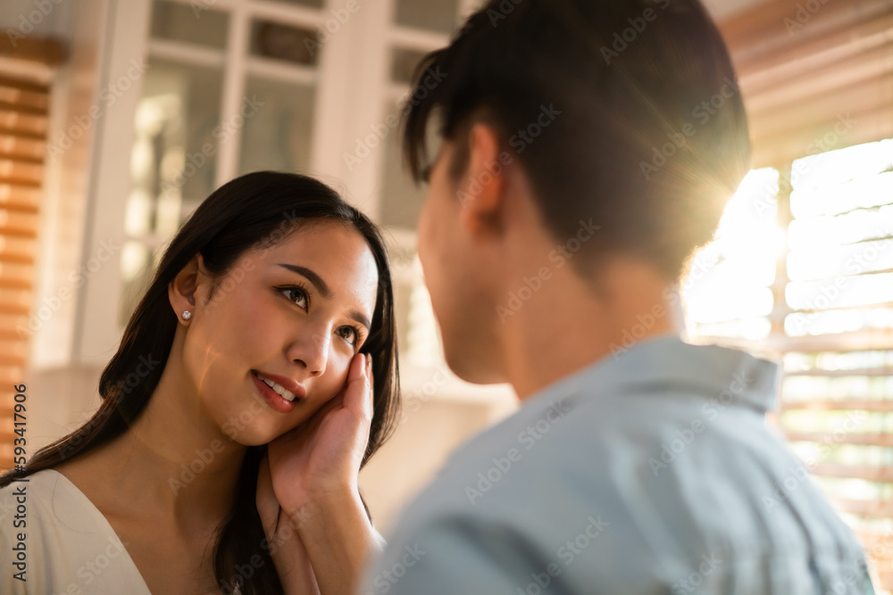 Asian young man and woman looking each other in living room at home. 