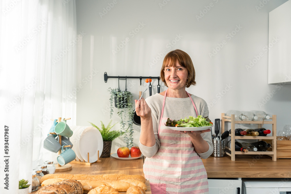 Portrait of Caucasian senior woman hold a bowl of vegetables in house. 