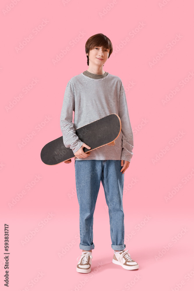 Teenage boy with skateboard on pink background