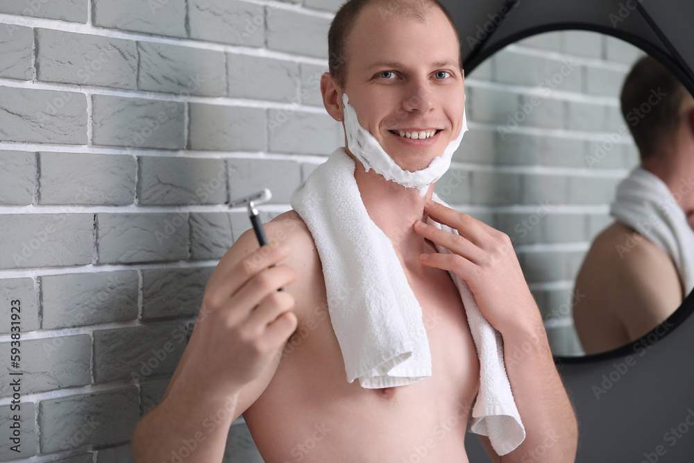 Young man shaving in bathroom