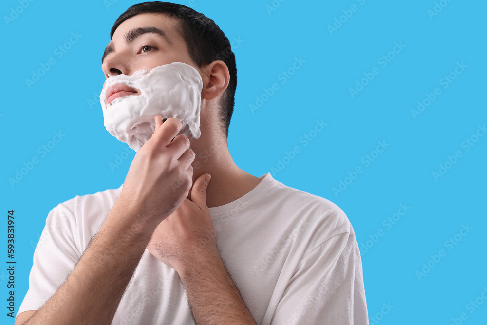 Young man shaving against light blue background