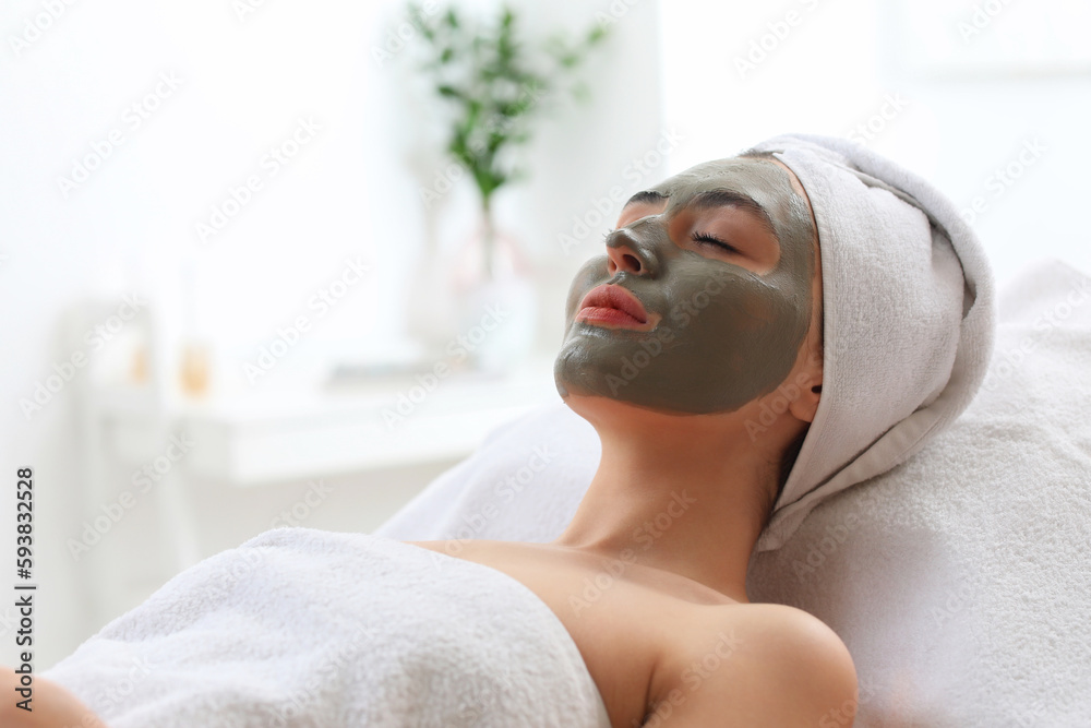 Young woman with applied clay mask in salon, closeup