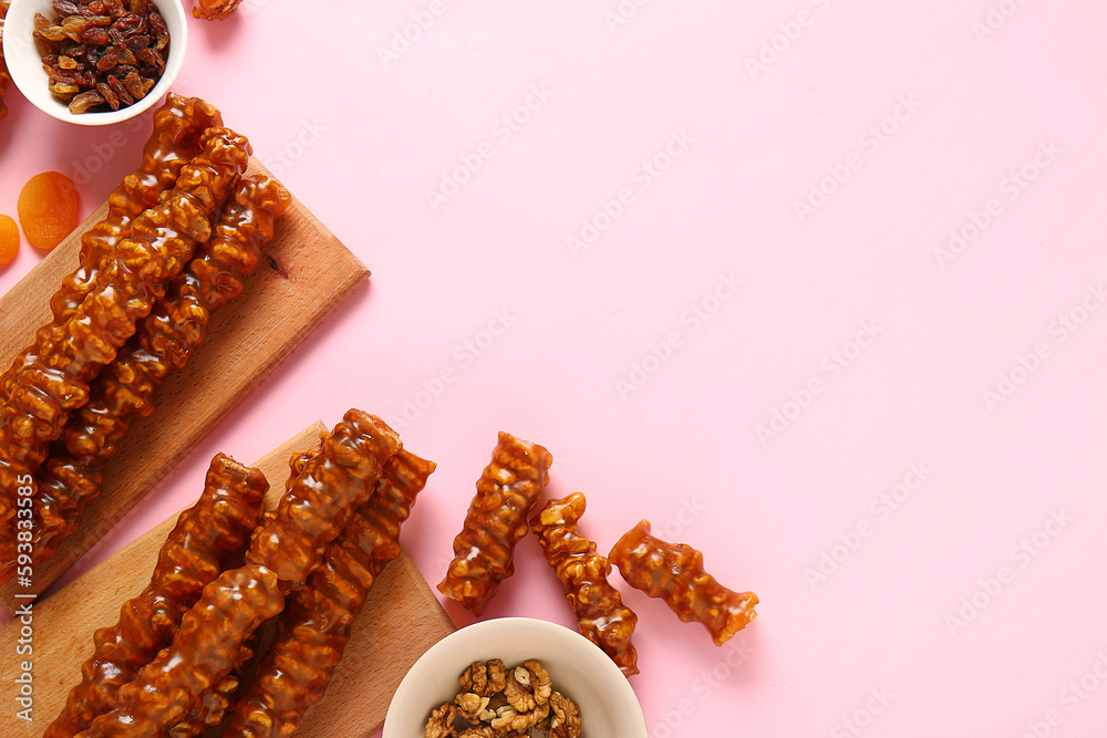 Tasty churchkhela, walnuts and raisin on pink background