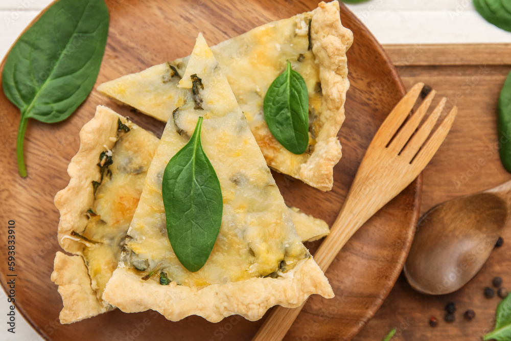 Pieces of delicious quiche on wooden plate