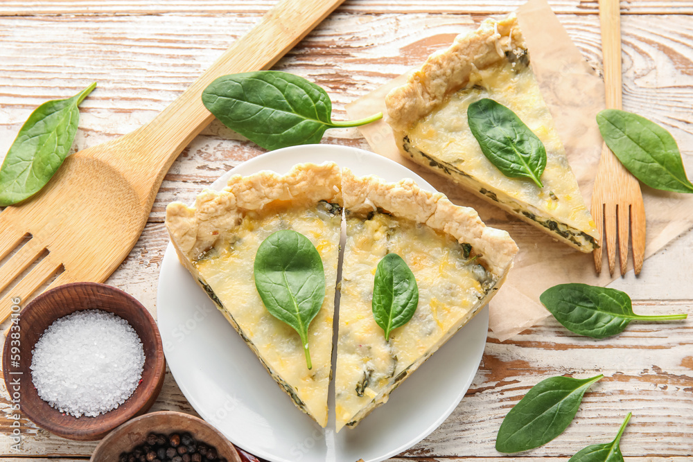 Plate with pieces of delicious quiche and salt on white wooden background