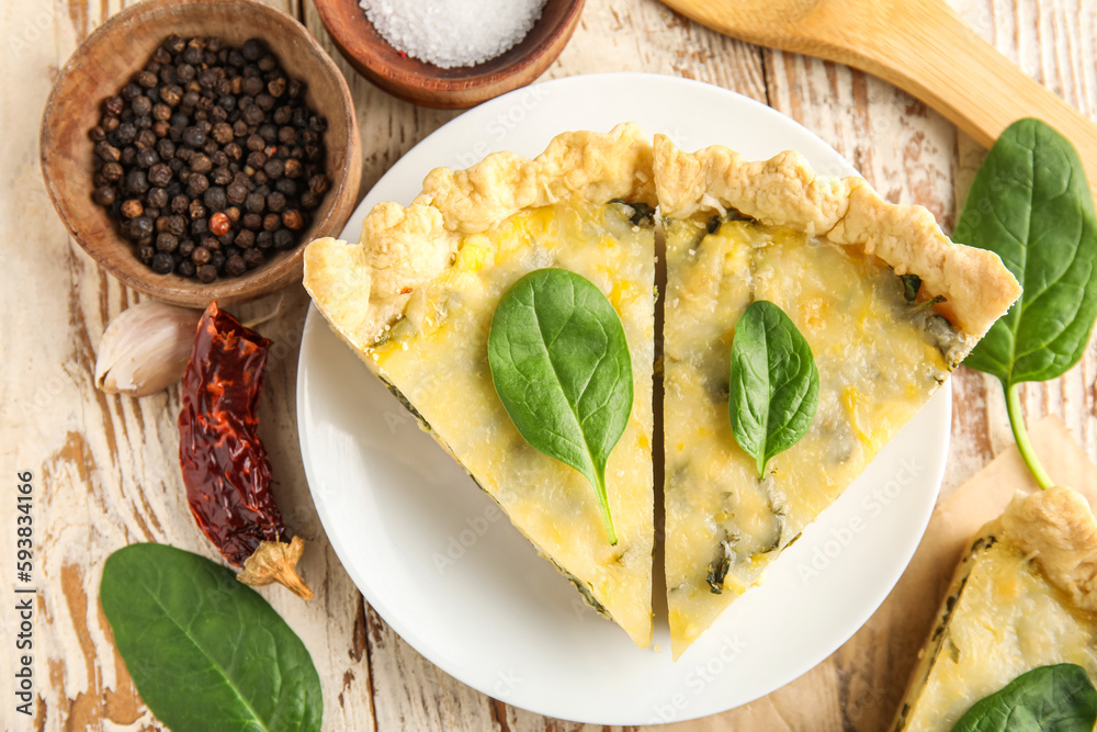 Plate with pieces of delicious quiche and peppercorn on white wooden background