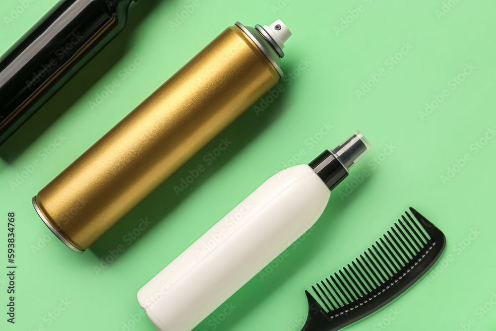 Bottles of hair sprays and comb on color background, closeup