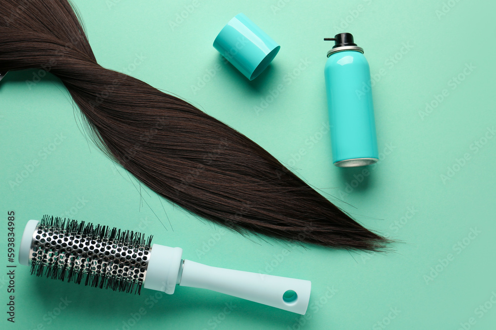 Bottle of hair spray, brush and strand on color background