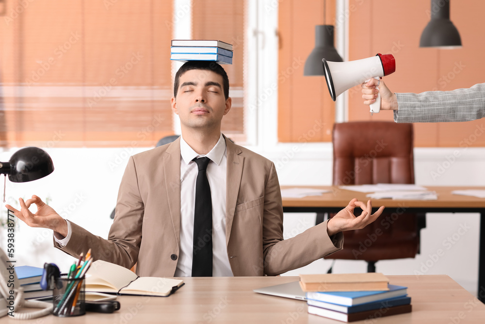 Young businessman with books meditating in office. Balance concept