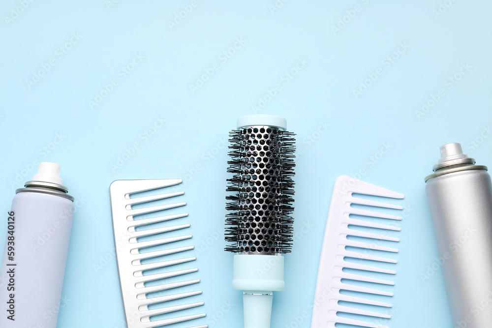 Hair brushes with spray bottles on blue background