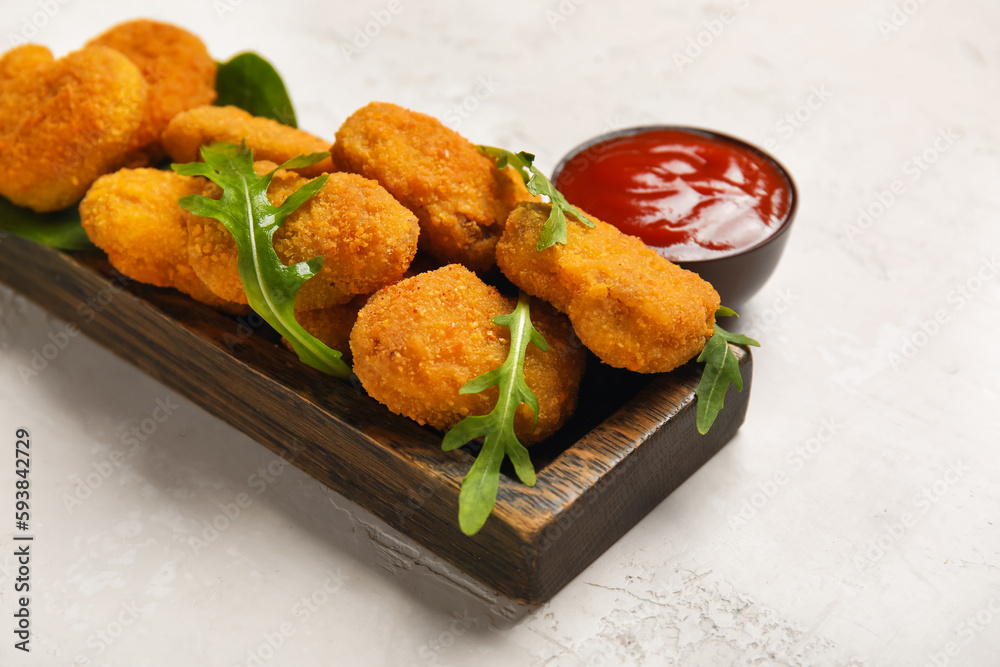 Wooden board with tasty nuggets and ketchup on light background, closeup