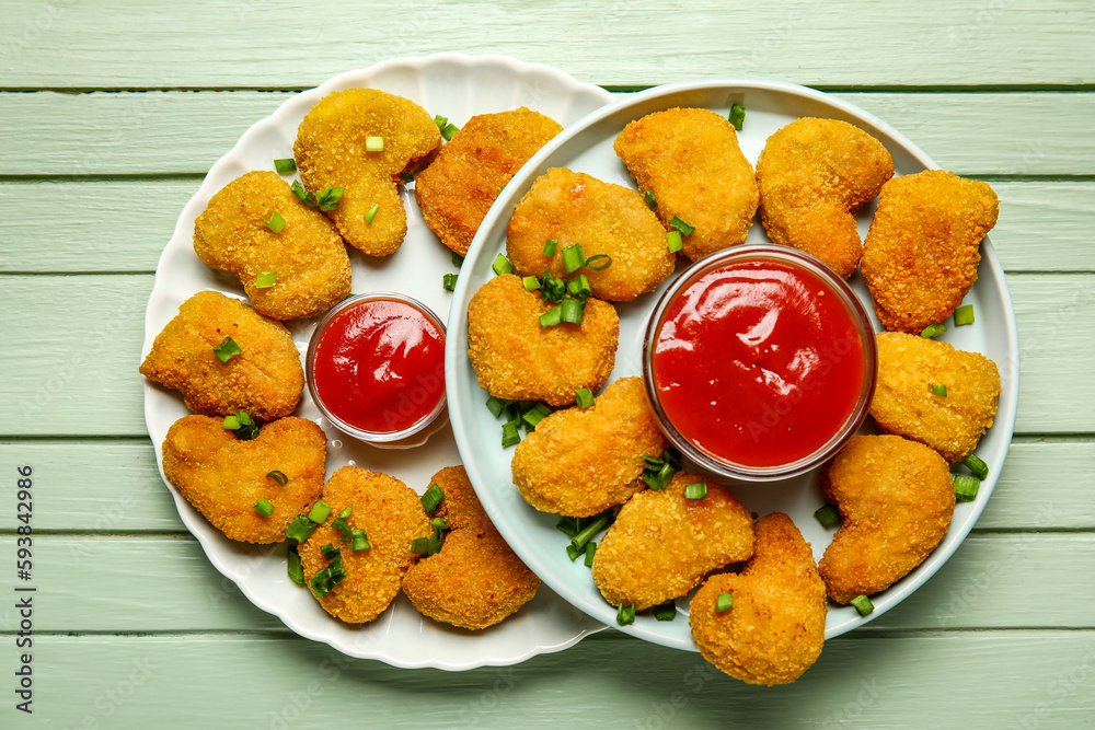 Plates of tasty nuggets with ketchup on green wooden background