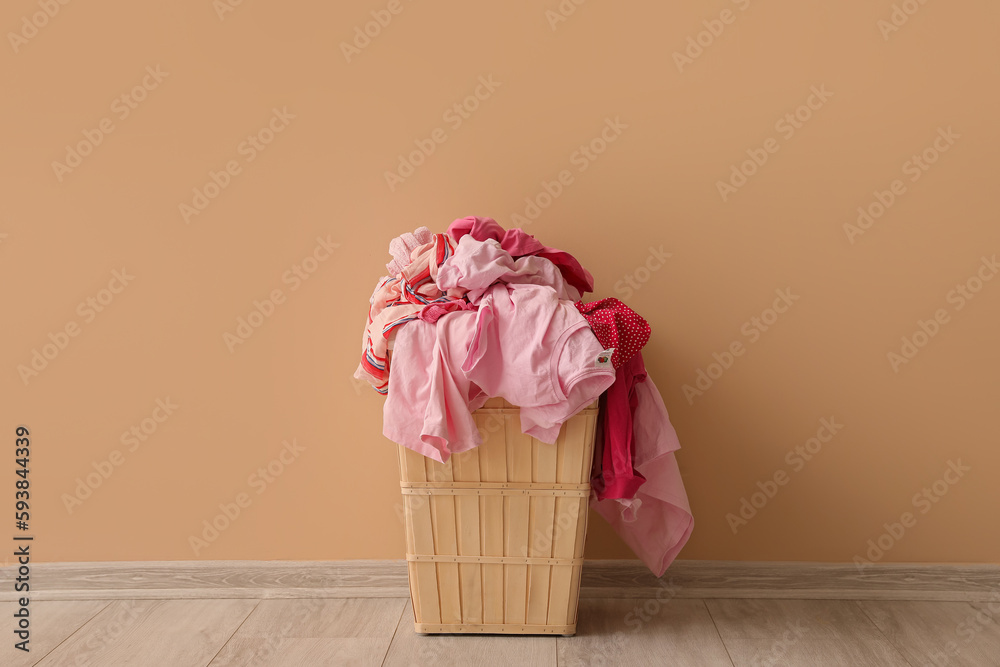 Basket with dirty clothes near beige wall