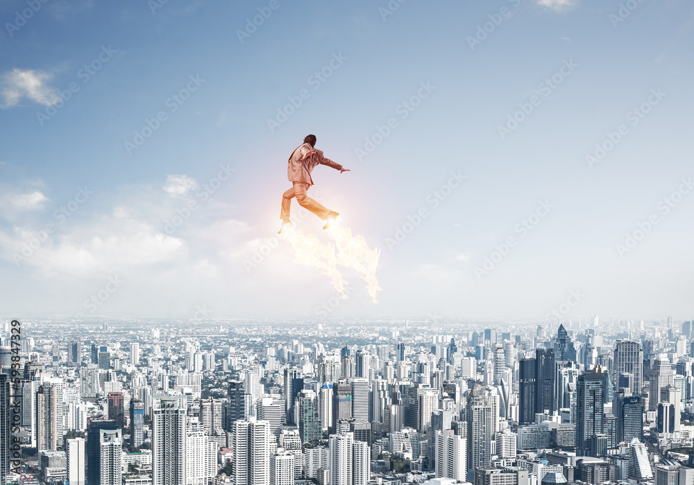 Businessman in suit and aviator hat flying in sky