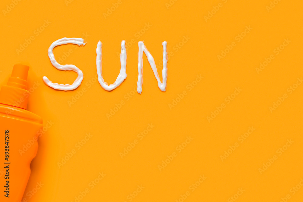 Word SUN made of sunscreen cream on orange background