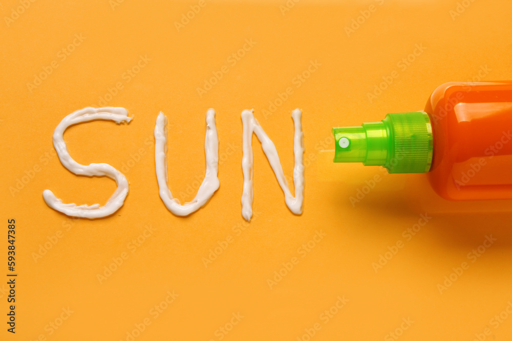 Word SUN made of sunscreen cream on orange background