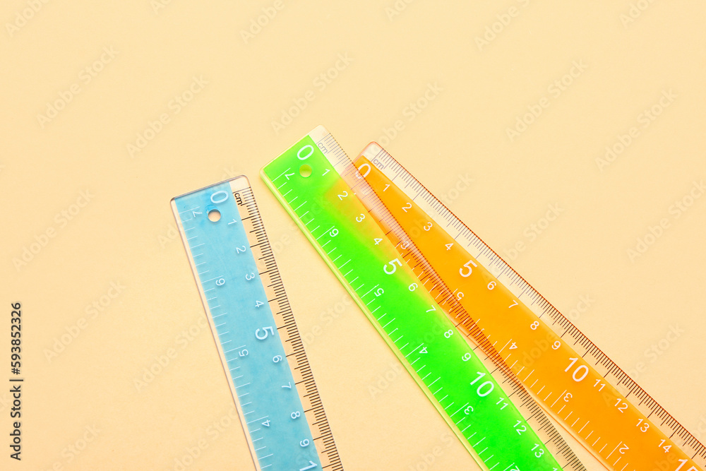 Colorful plastic rulers on beige background