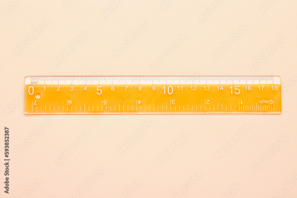 Orange plastic ruler on beige background