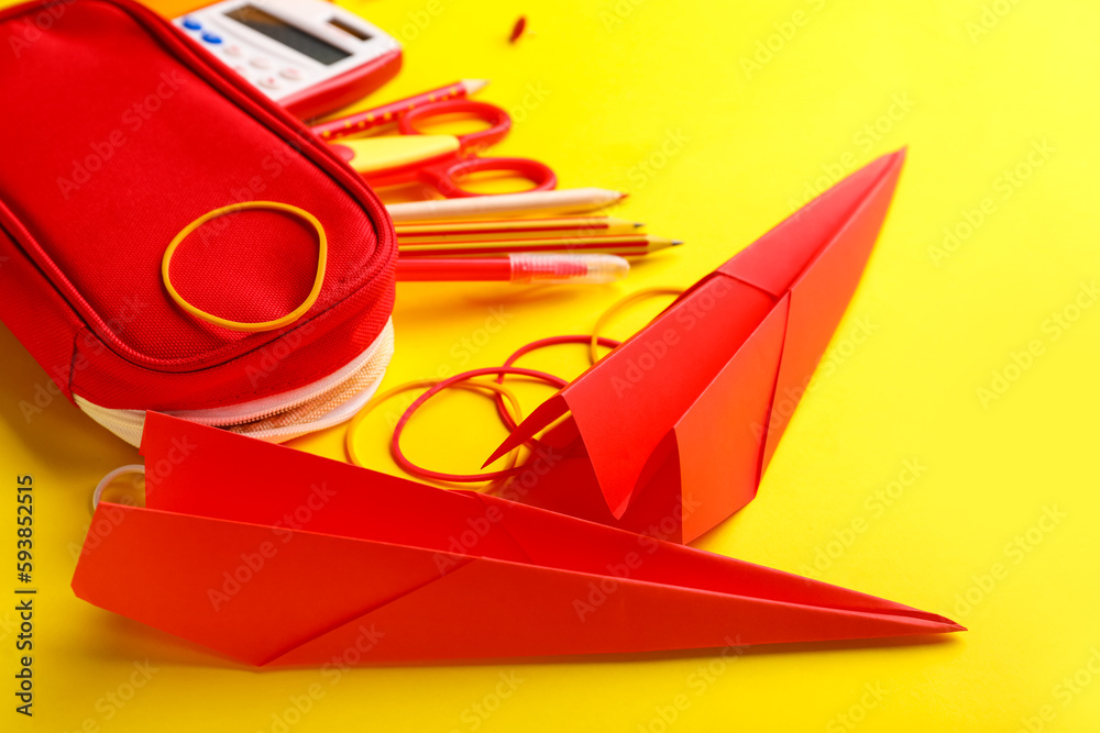 Composition with stationery supplies and paper planes on yellow background