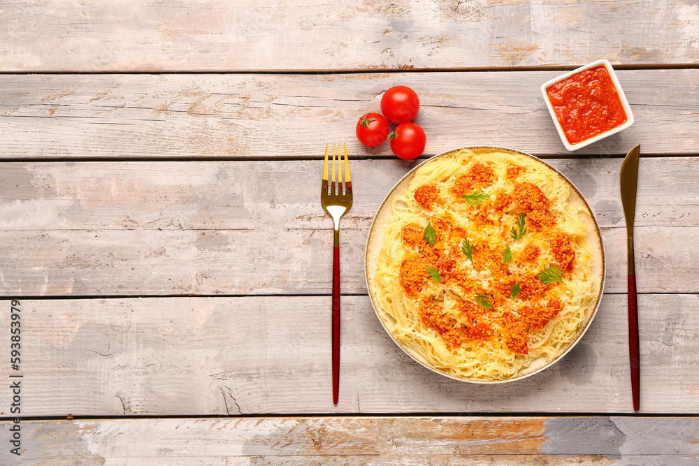 Plate of tasty Italian pasta with Parmesan cheese and sauce on light wooden background