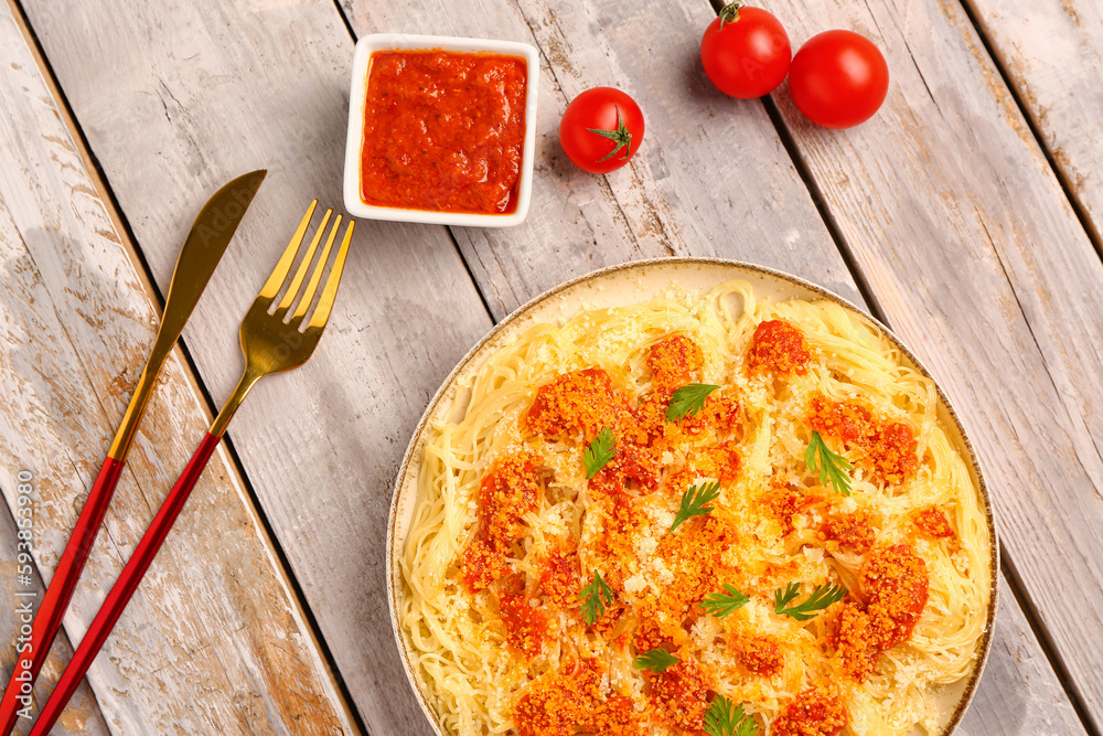 Plate of tasty Italian pasta with Parmesan cheese and sauce on light wooden background