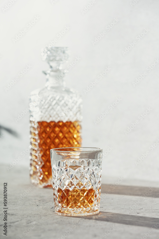 Glass of whiskey with ice cubes and carafe close up