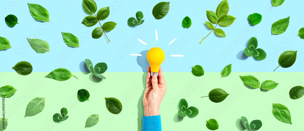 Person holding a light bulb with green leaves