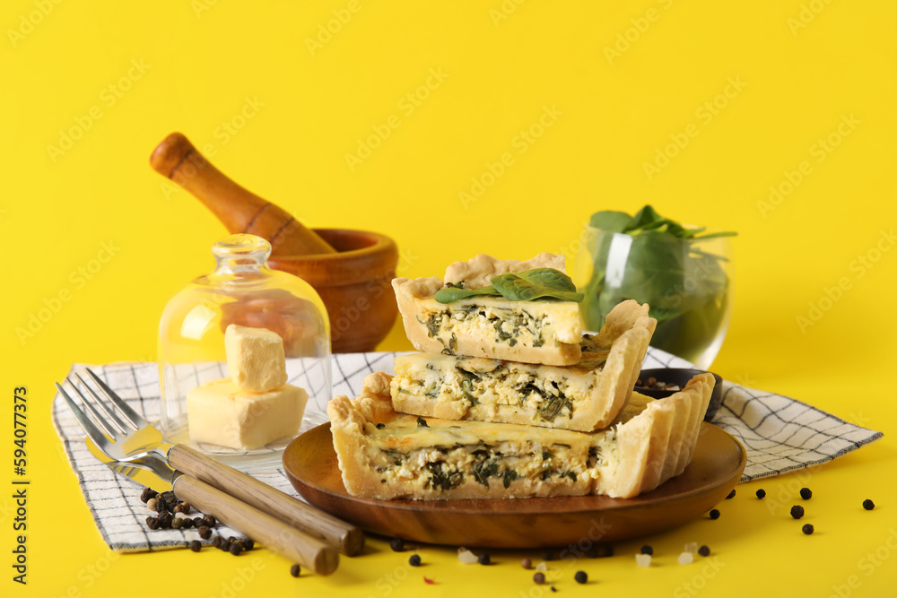 Board with pieces of delicious quiche on yellow background