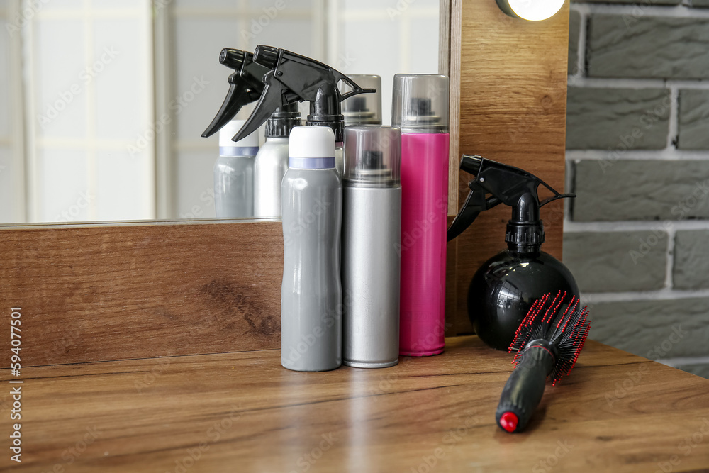 Different hair sprays on table in beauty salon