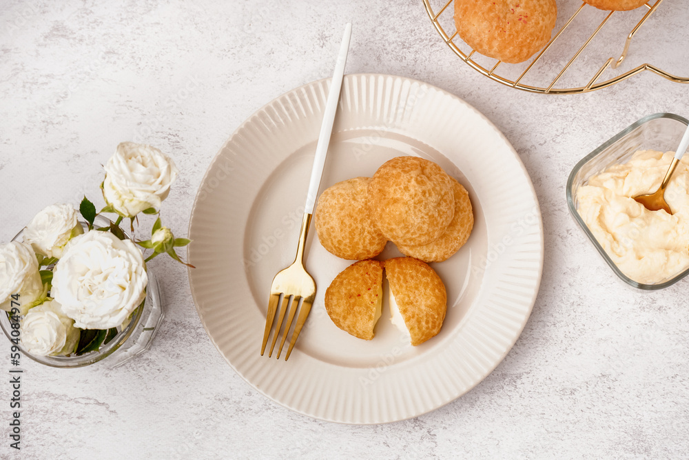 Plate with tasty choux dessert on light background