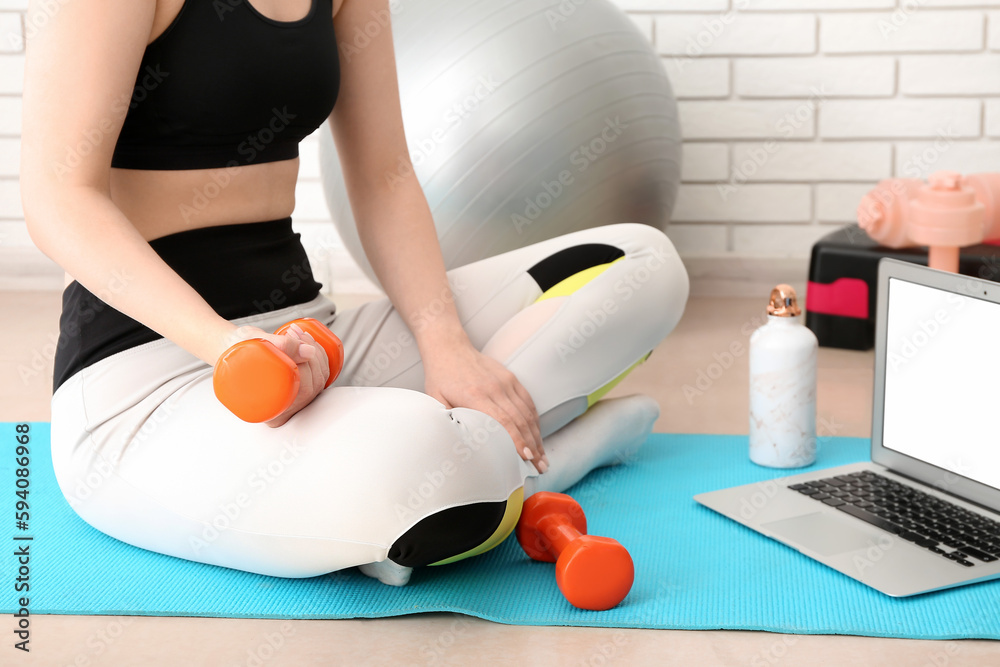 Sporty woman training with dumbbells in gym