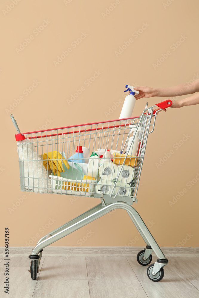 Shopping cart with cleaning supplies near beige wall