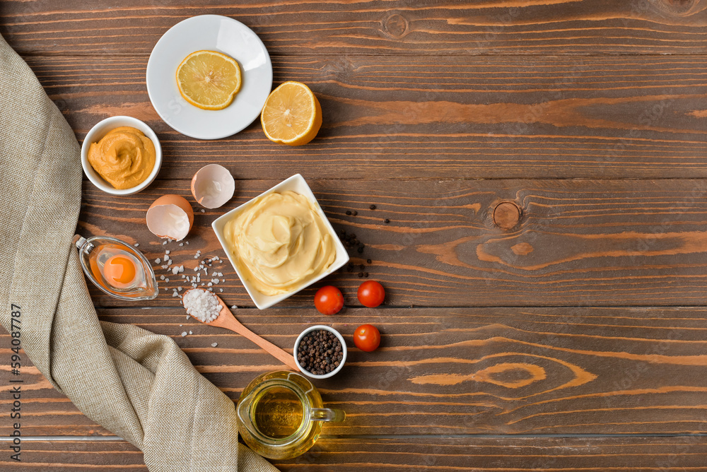 Bowl with tasty mayonnaise sauce and ingredients on wooden background