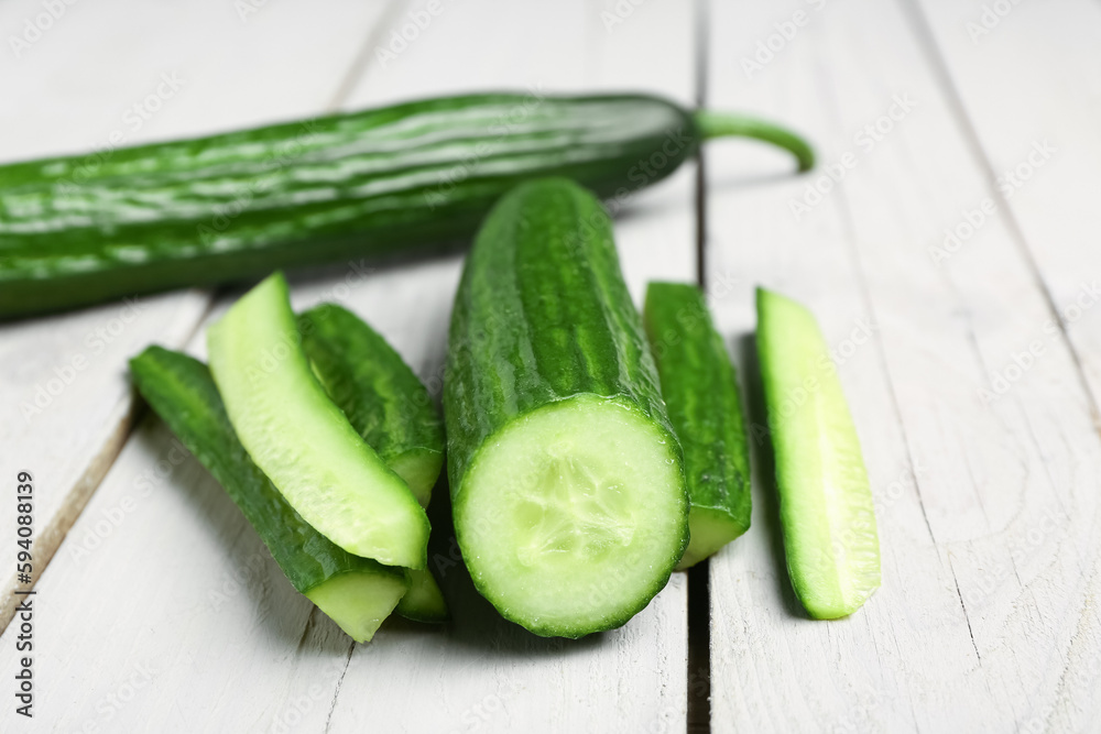 Fresh cut cucumber on light wooden background, closeup