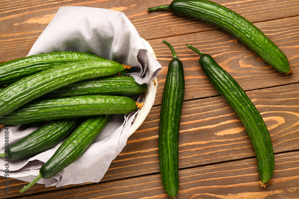 Basket with fresh cucumbers on wooden background