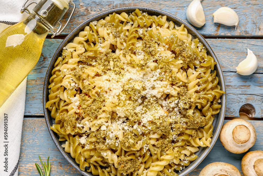 Plate of tasty Italian pasta with Parmesan cheese on blue wooden background