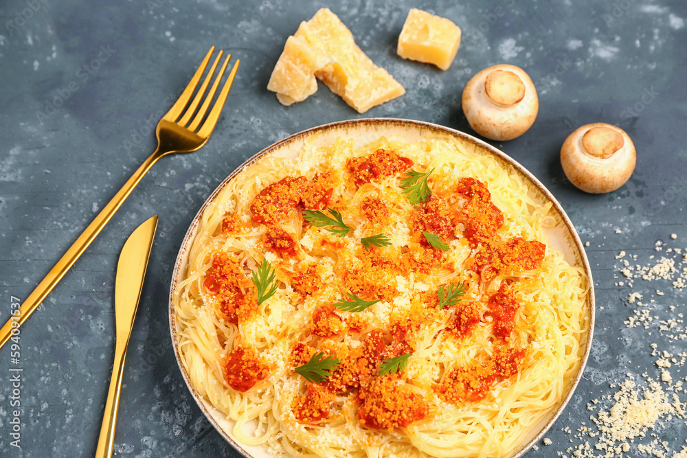 Plate of tasty Italian pasta with Parmesan cheese on blue background