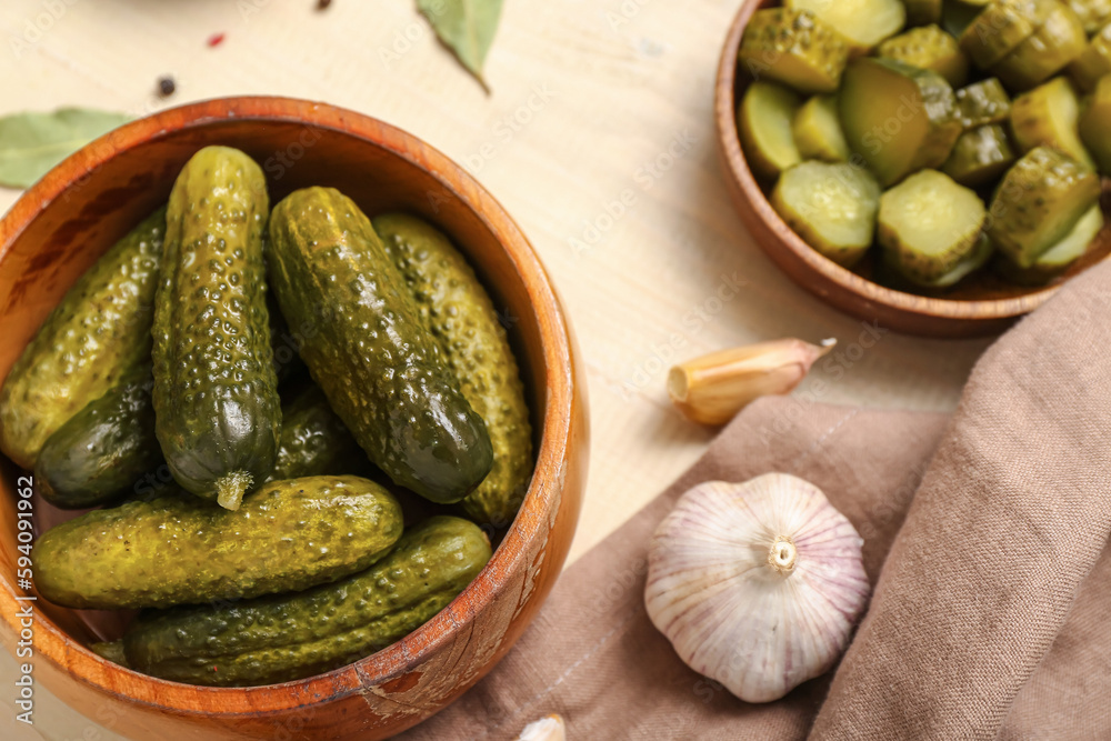 Bowl with tasty fermented cucumbers on light wooden background