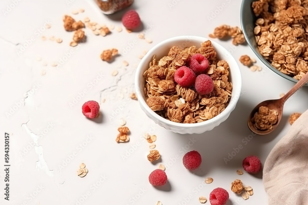  a bowl of granola with raspberries and a spoon next to it on a white surface with scattered raspber