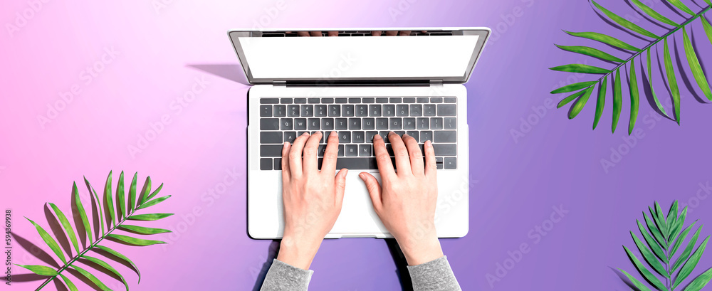 Person using a laptop computer with tropical leaves from above