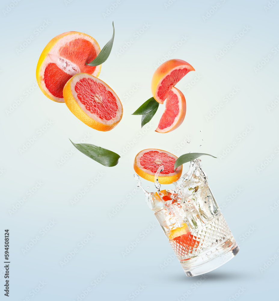 Glass of water and grapefruit slices on light background